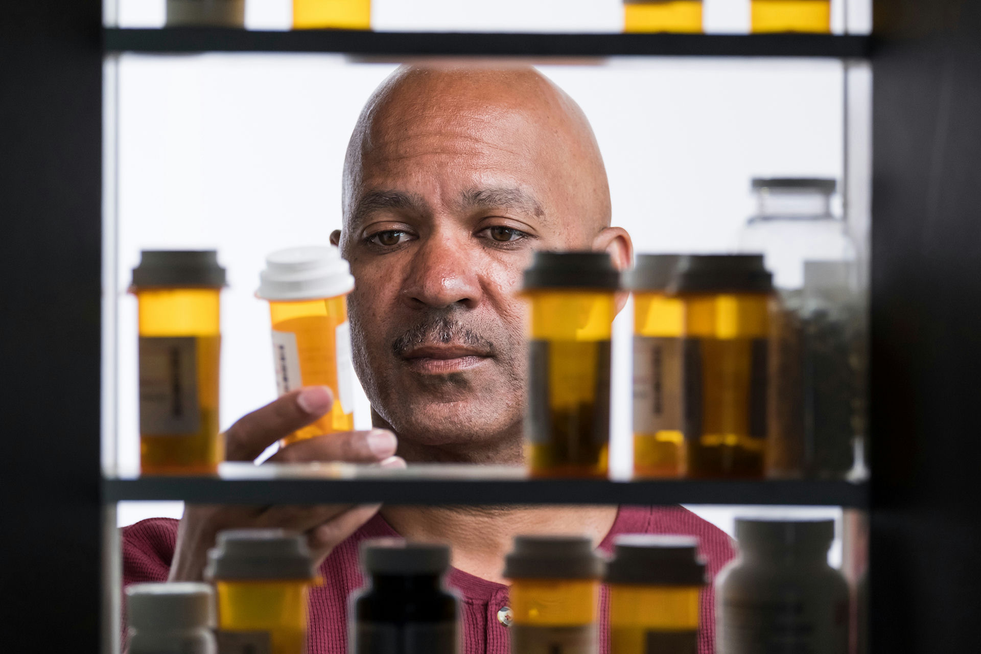 Older man examining a prescription bottle among many others, highlighting dependency issues and the importance of seeking opioid rehab programs.